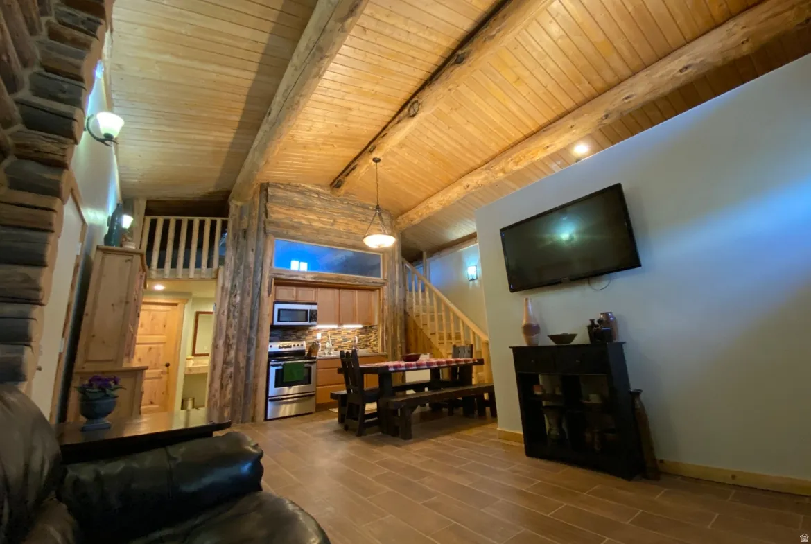 Living area with wood finish floors, wood ceiling, vaulted ceiling with beams, and track lighting