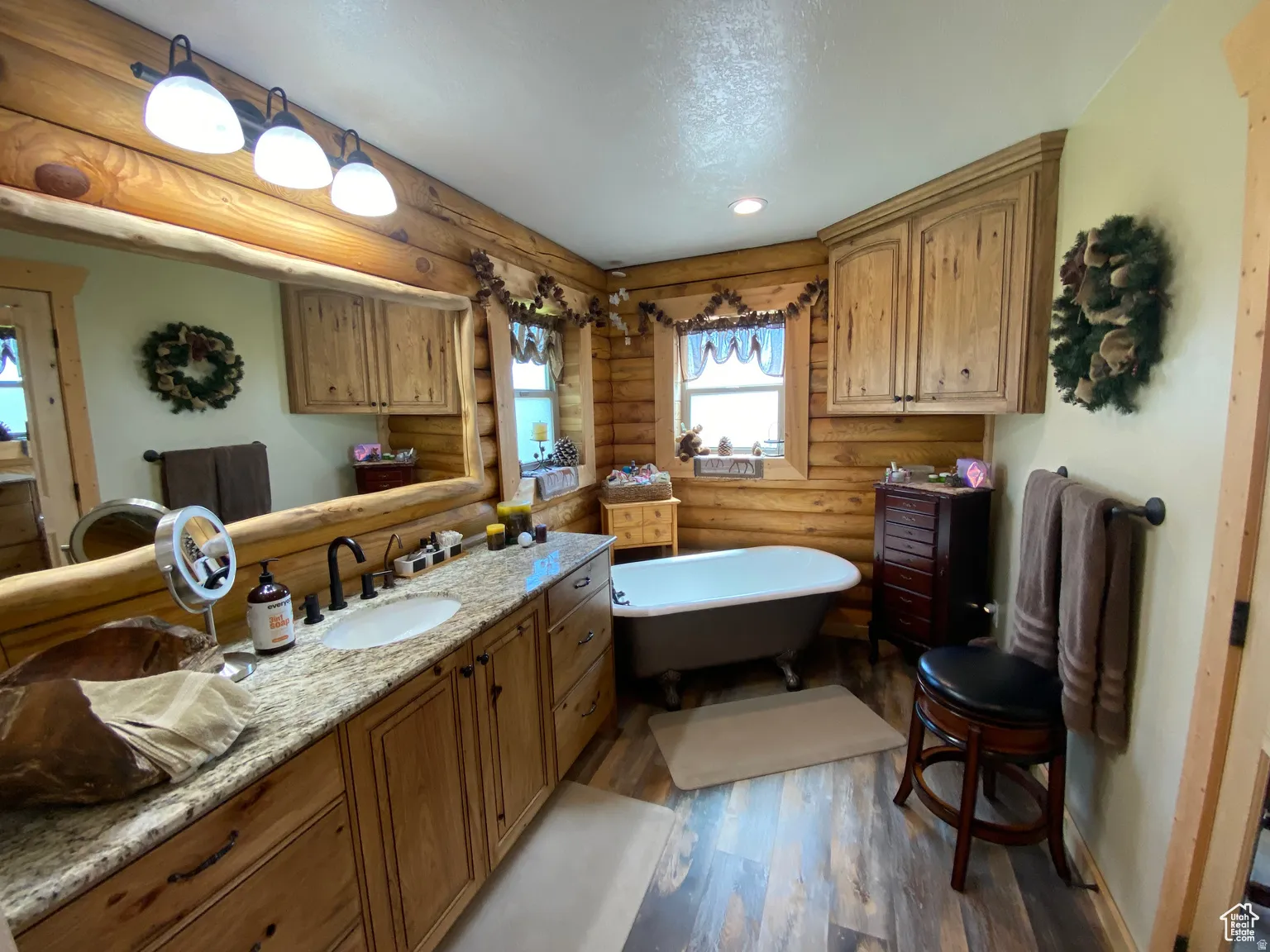Full bathroom featuring rustic walls, vanity, a soaking tub, dark wood-style floors, and recessed lighting