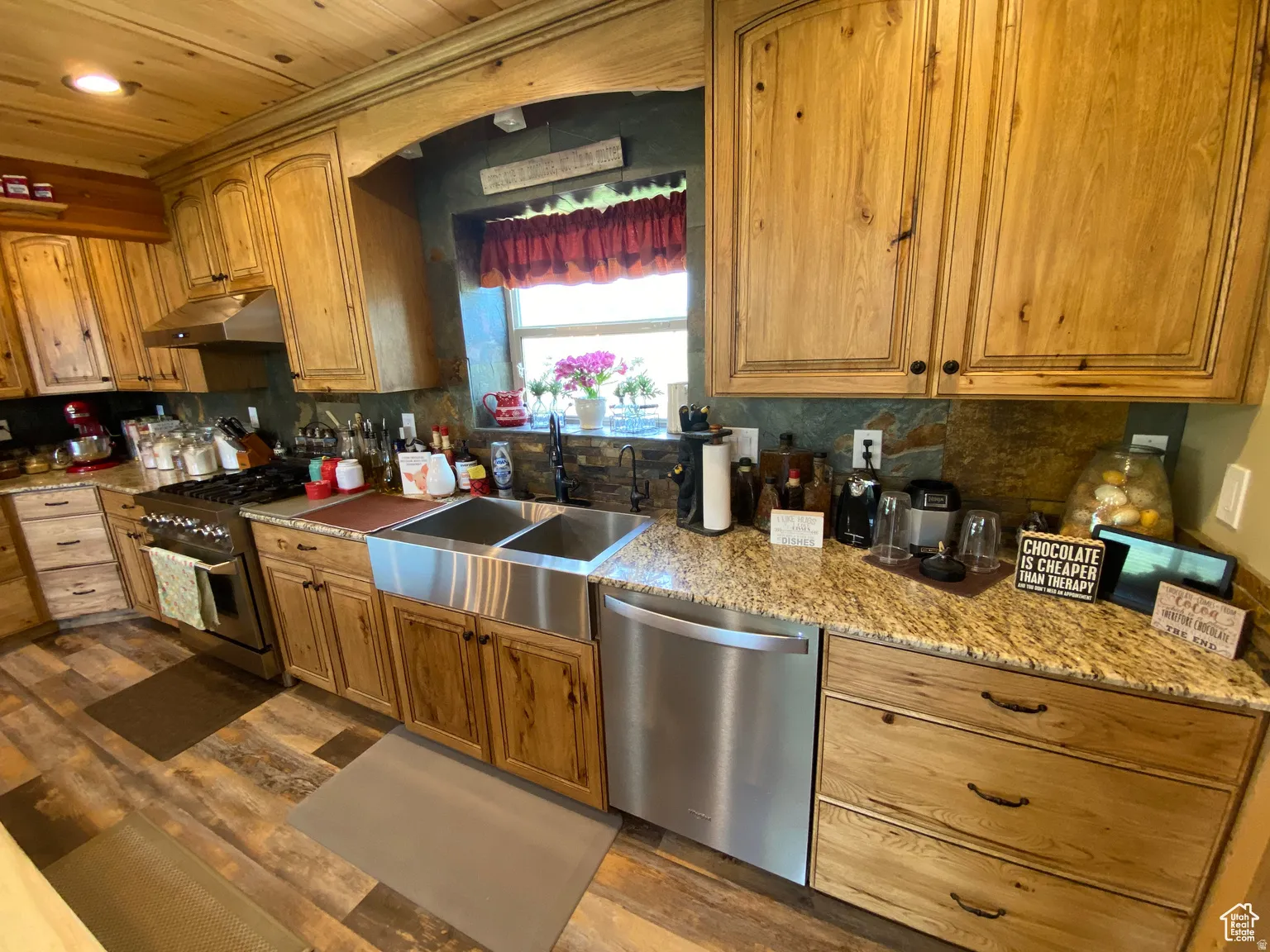 Kitchen with stainless steel appliances, light stone counters, wood finish cabinets, dark wood-style floors, and wooden ceiling