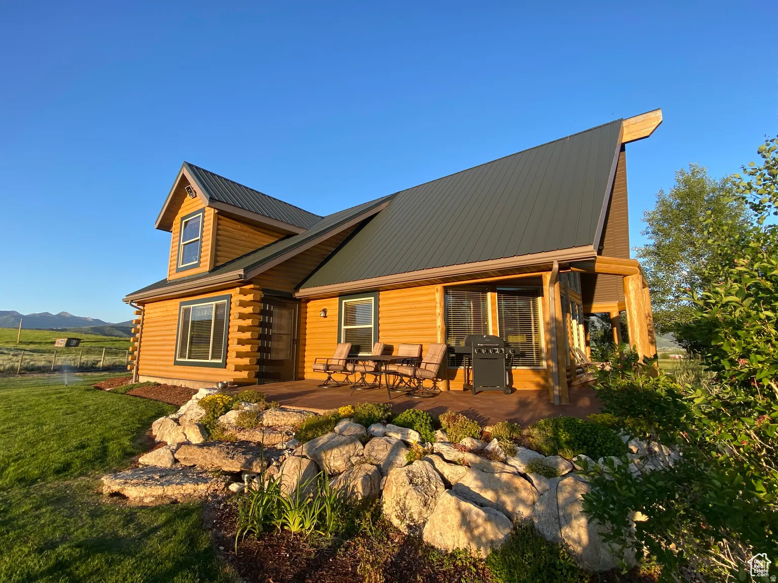 View of front of house featuring a metal roof, a patio, log exterior, and a mountain view