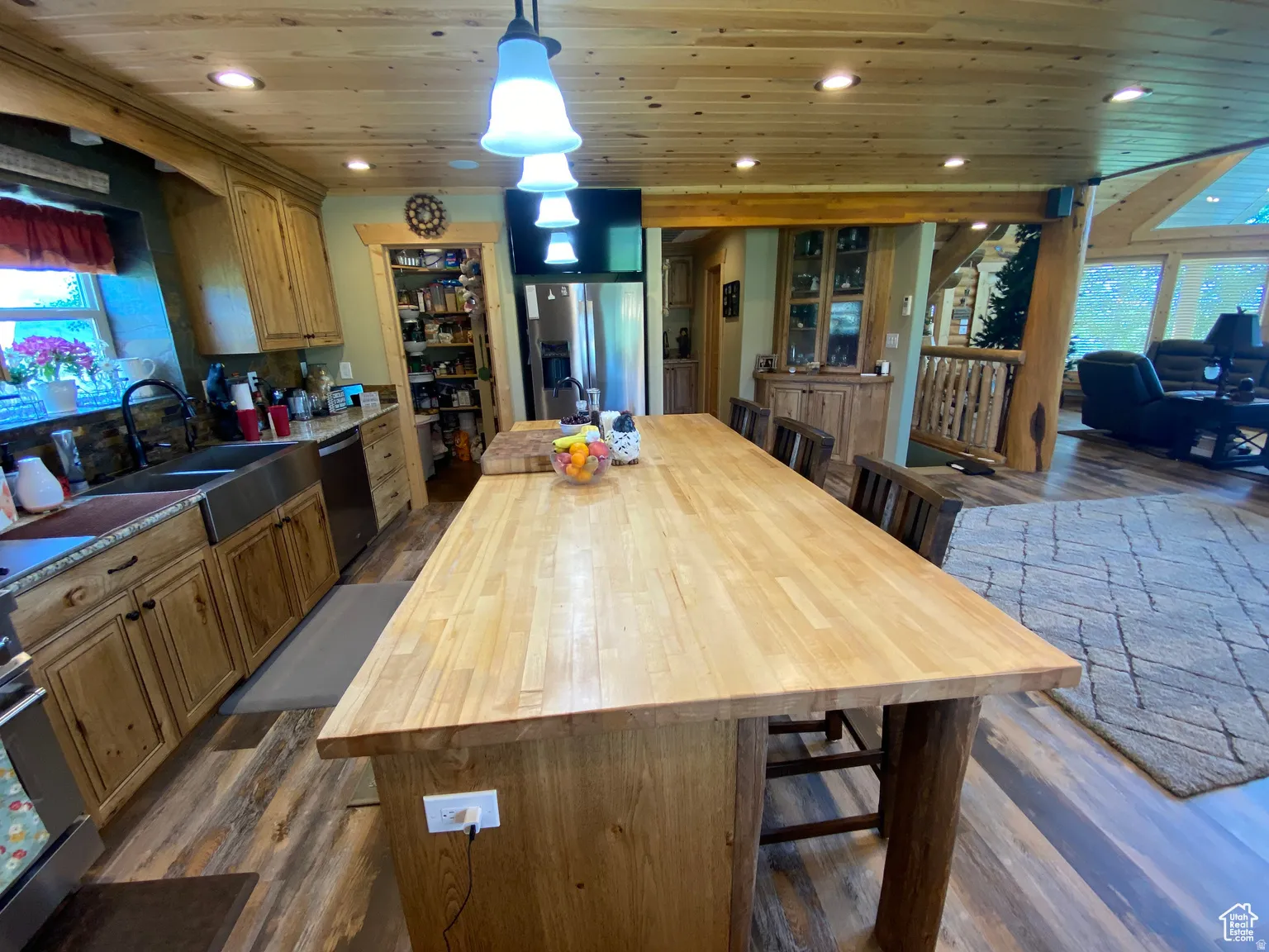 Kitchen featuring butcher block countertops, dark wood-style floors, a kitchen breakfast bar, an island with sink, and wood ceiling