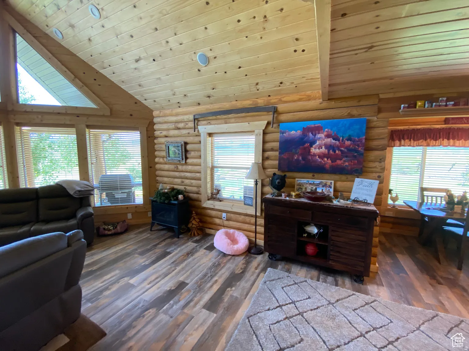Living area featuring a vaulted wood ceiling, plenty of natural light, dark wood-type flooring, and rustic walls
