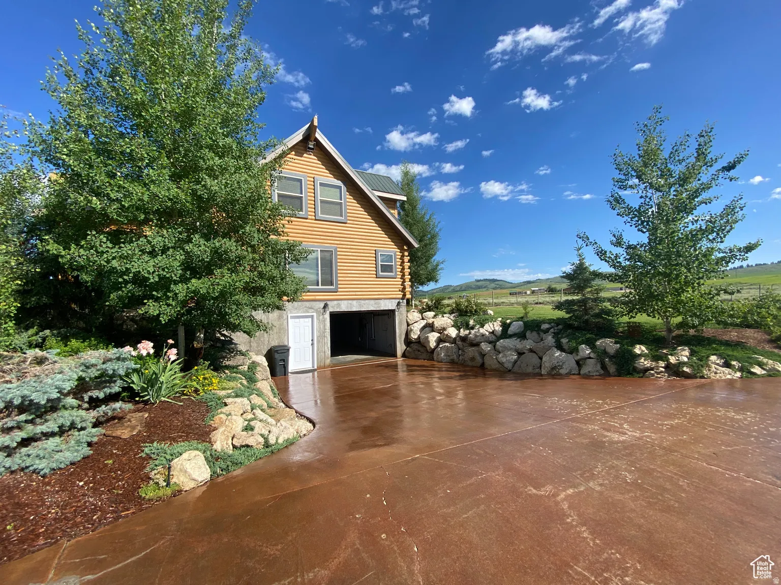 View of side of property featuring driveway, a garage, a metal roof, and log siding