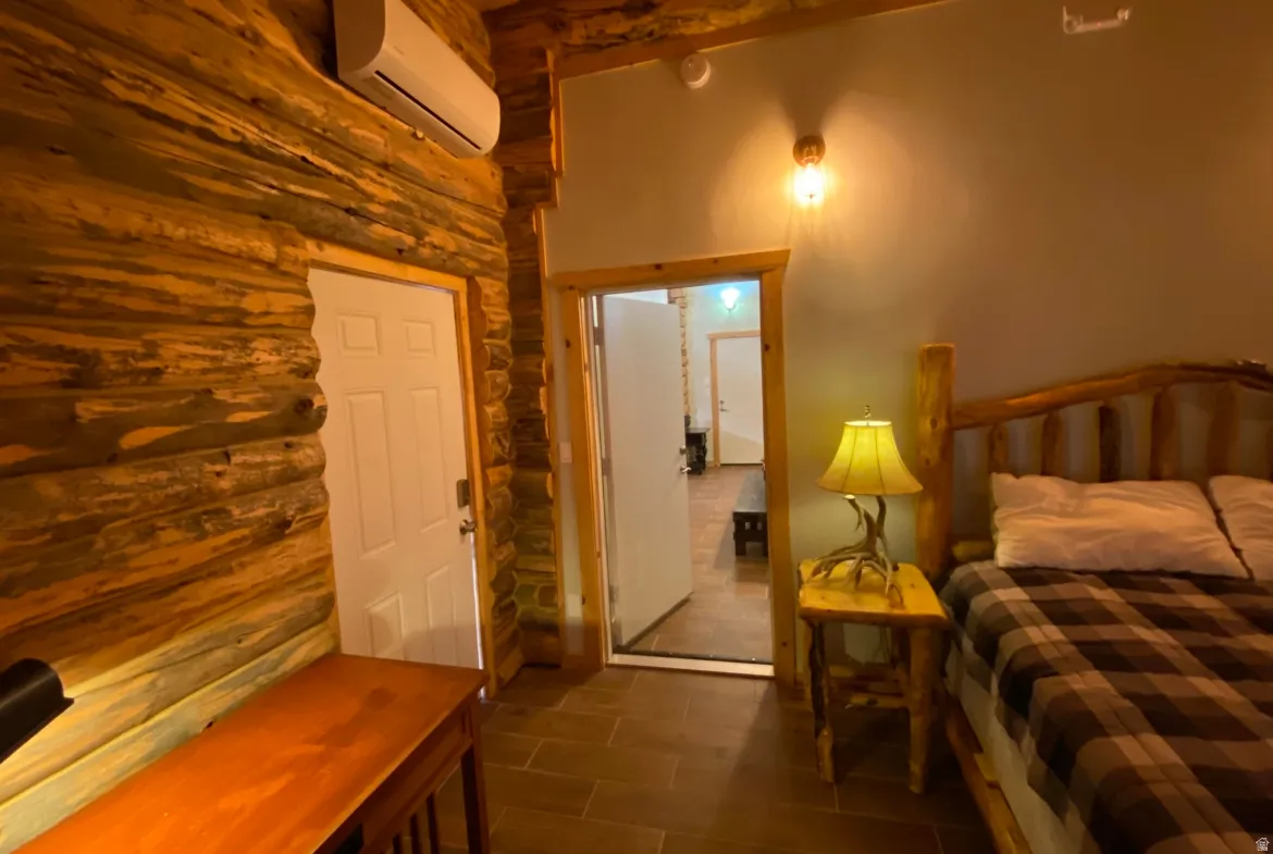 Bedroom with a wall mounted mini split and log walls