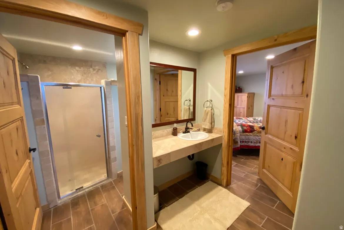 Bathroom with wood finish floors, ensuite bath, vanity, a shower stall, and recessed lighting