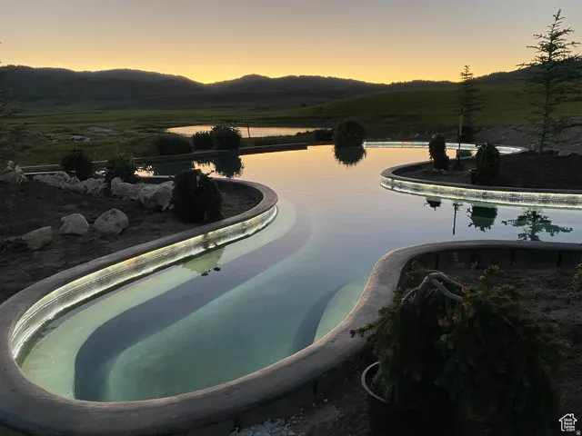 Pool at dusk with a mountain view and an infinity pool