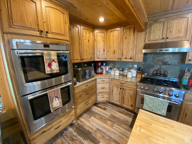 Kitchen featuring stainless steel appliances, wood counters, a wood ceiling with exposed beams, backsplash, and light wood-style flooring