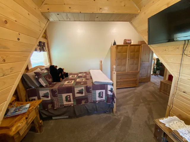 Bedroom featuring wooden ceiling, dark colored carpet, and lofted ceiling with beams