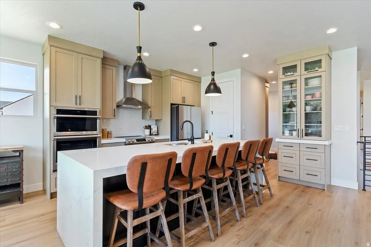 Kitchen featuring stainless steel appliances, a kitchen breakfast bar, a center island with sink, and cream cabinets