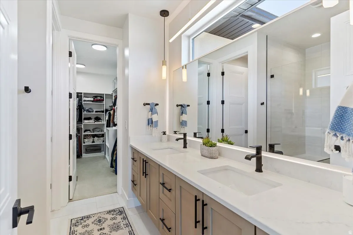 Full bathroom featuring a walk in closet, double vanity, a shower stall, and recessed lighting