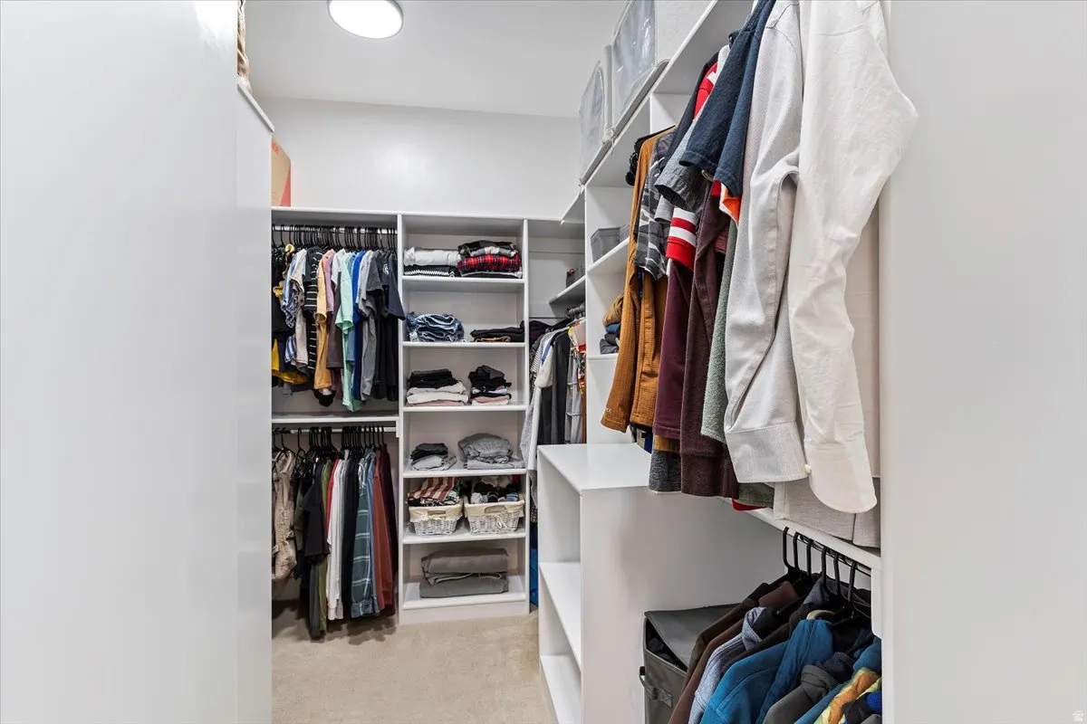 Walk in closet featuring light colored carpet
