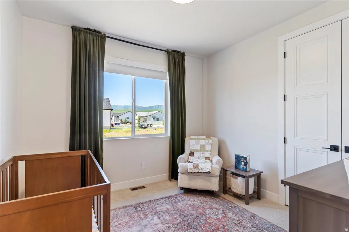Bedroom with light carpet and a crib