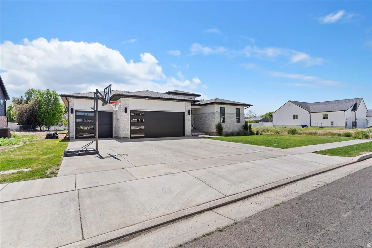 Prairie-style house featuring a garage, concrete driveway, a front lawn, and stone siding