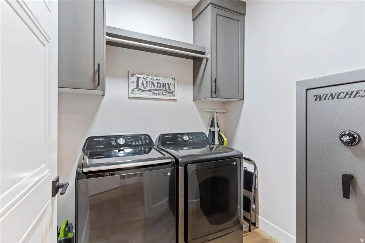 Laundry area with cabinet space, washer and clothes dryer, and light wood-style floors