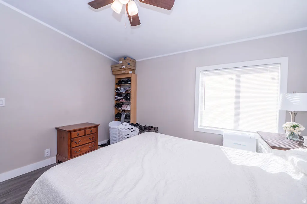 Bedroom with a ceiling fan, crown molding, and dark wood-style floors