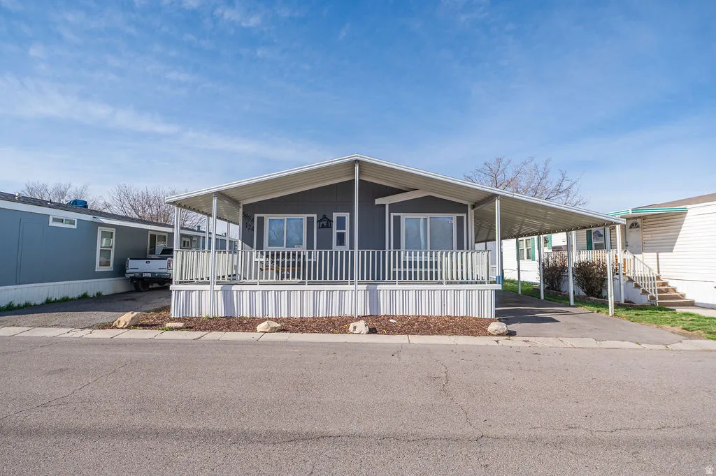 Manufactured / mobile home with a large porch, an attached carport, and driveway