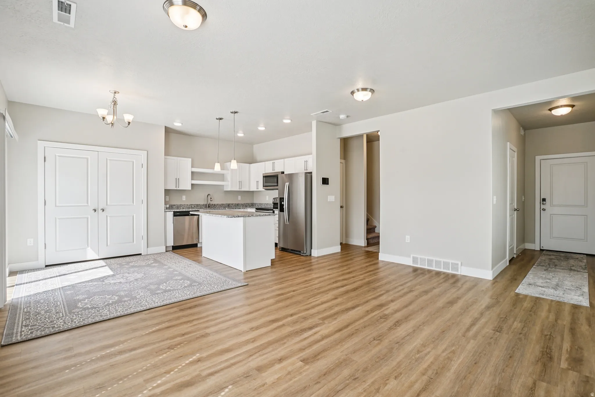 Kitchen featuring white cabinetry, open floor plan, stainless steel appliances, a kitchen island, and light wood-type flooring