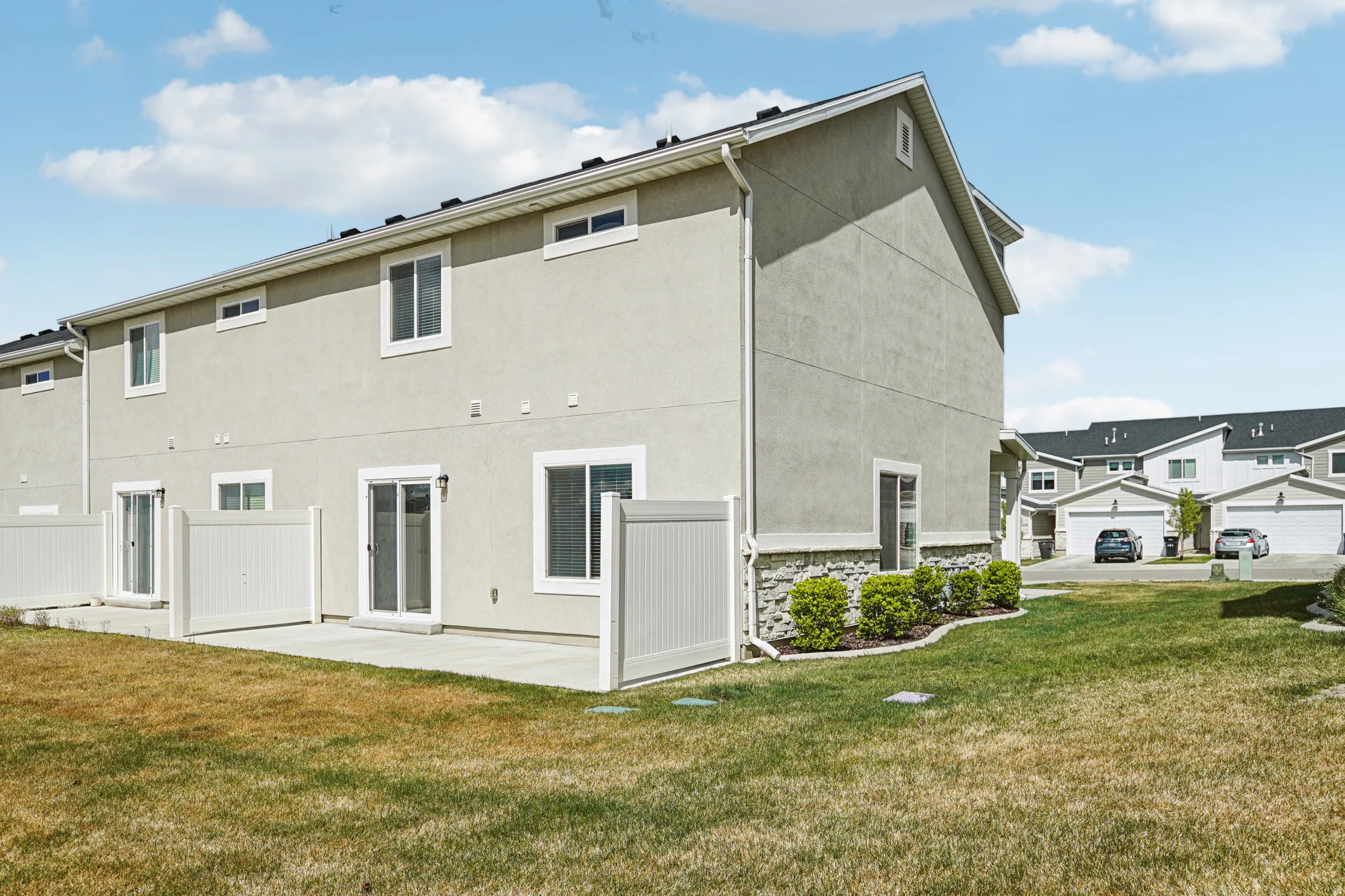 Rear view of property featuring a yard, stucco siding, and stone siding