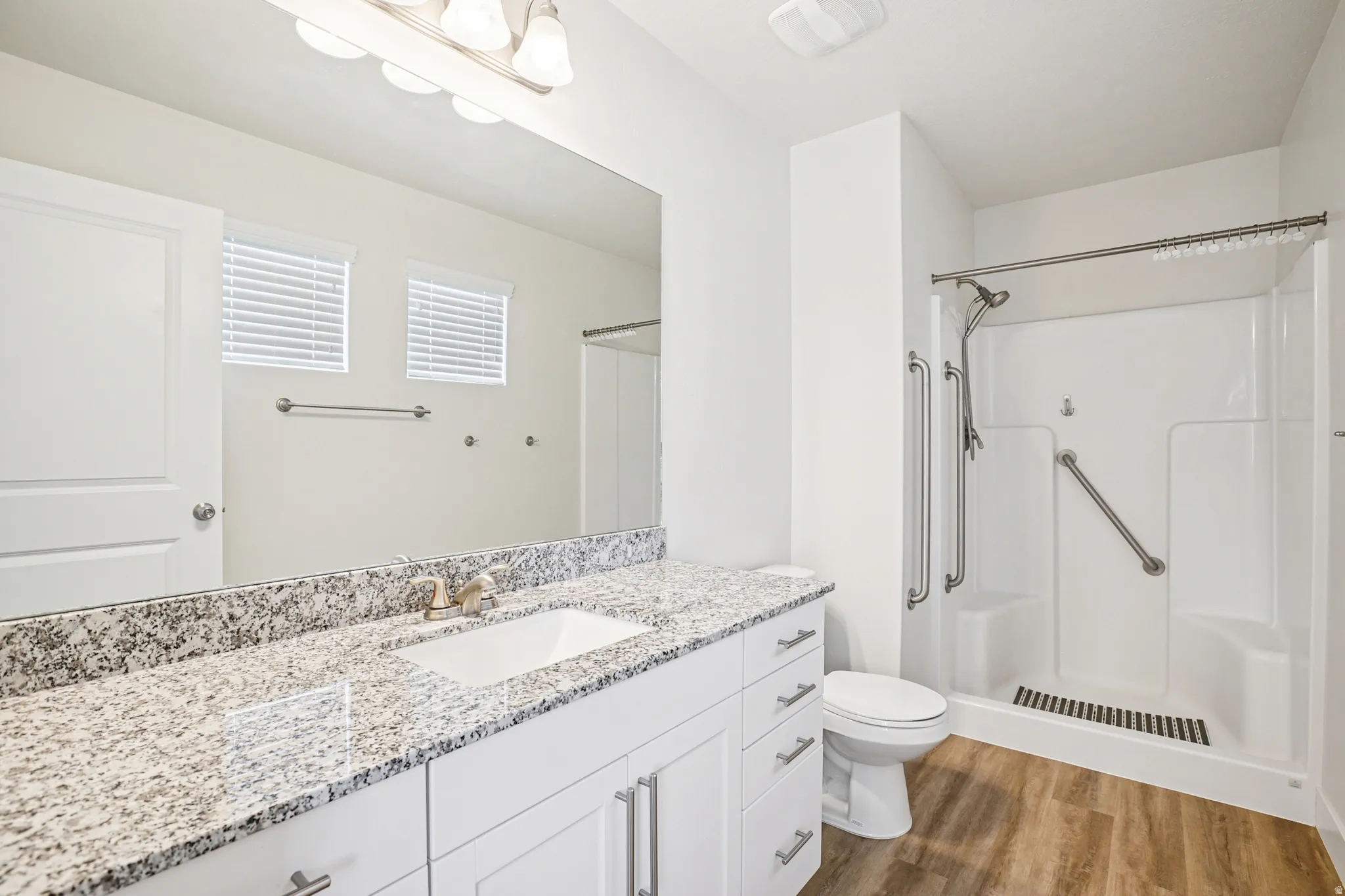 Full bathroom featuring vanity, a shower stall, and dark wood finished floors