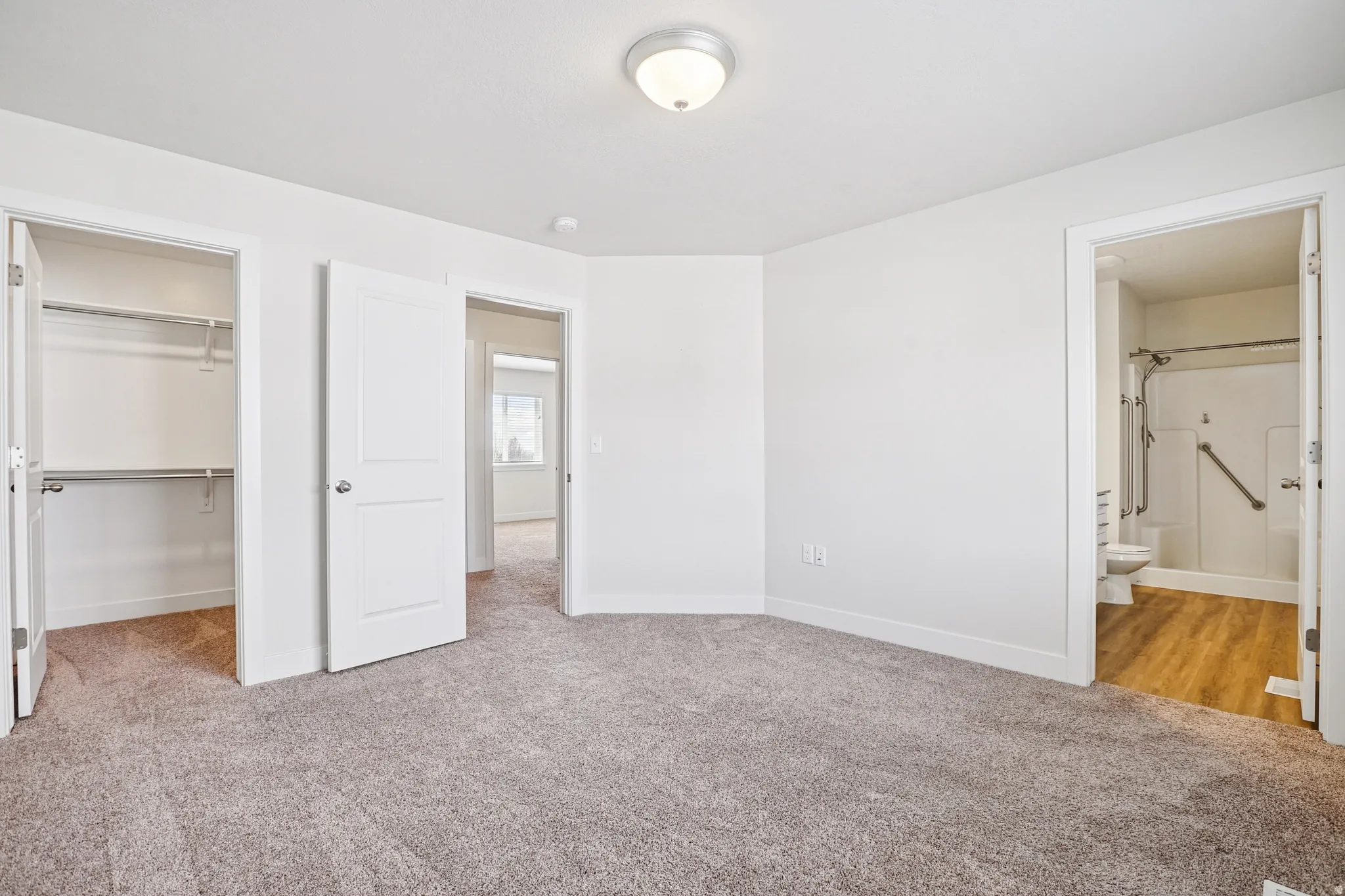 Unfurnished bedroom featuring light colored carpet, a walk in closet, and connected bathroom