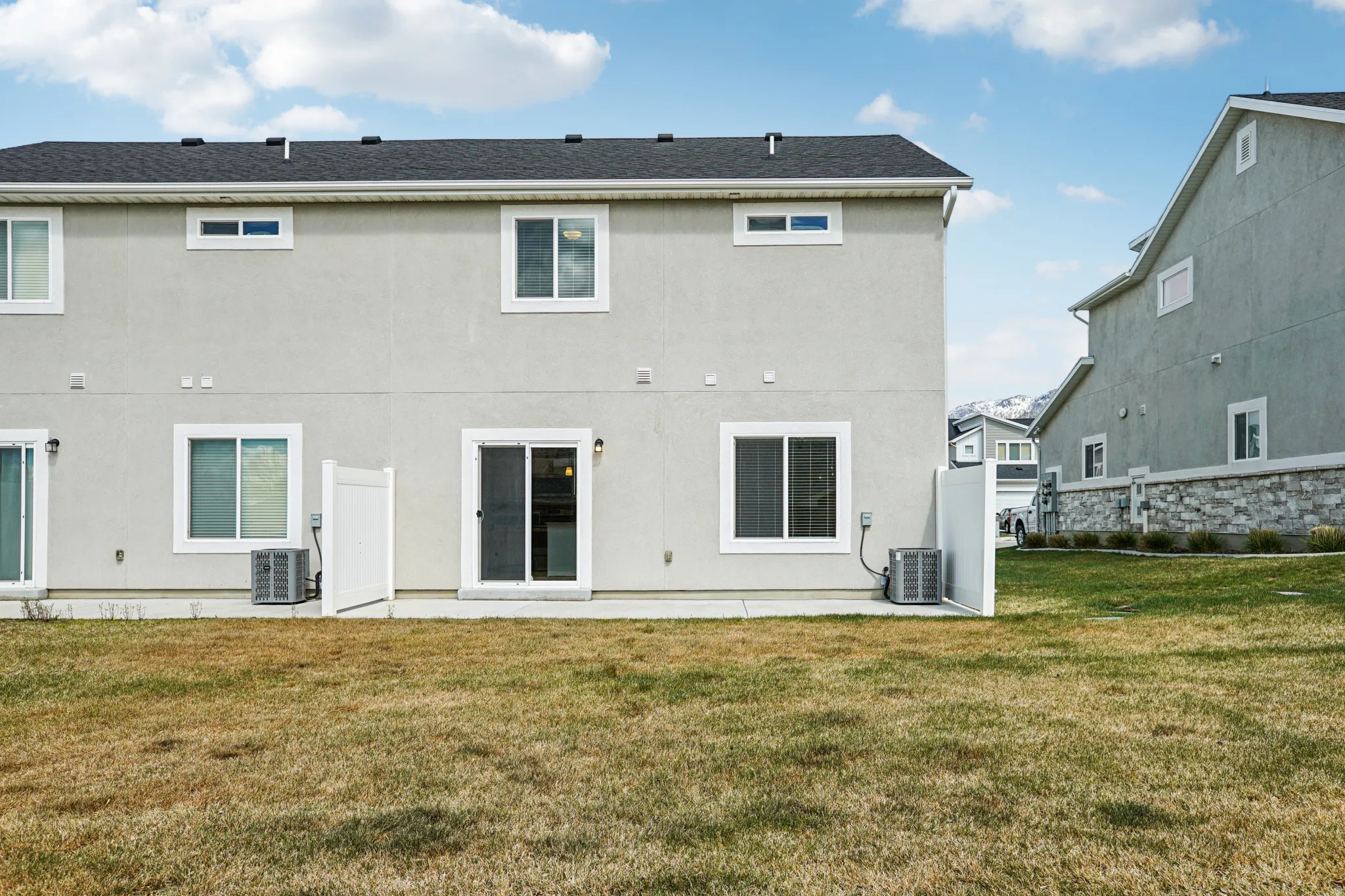 Rear view of house with a lawn, stucco siding, and a patio area