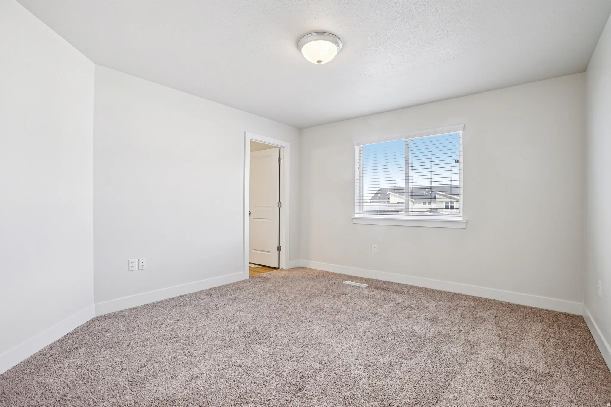 Spare room with baseboards and light colored carpet