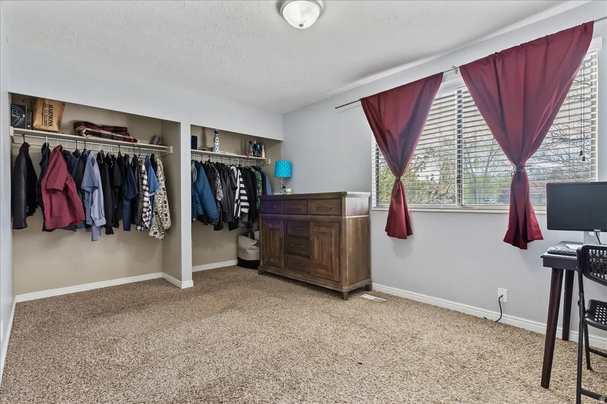 Primary Bedroom with light carpet, a textured ceiling, and multiple closets