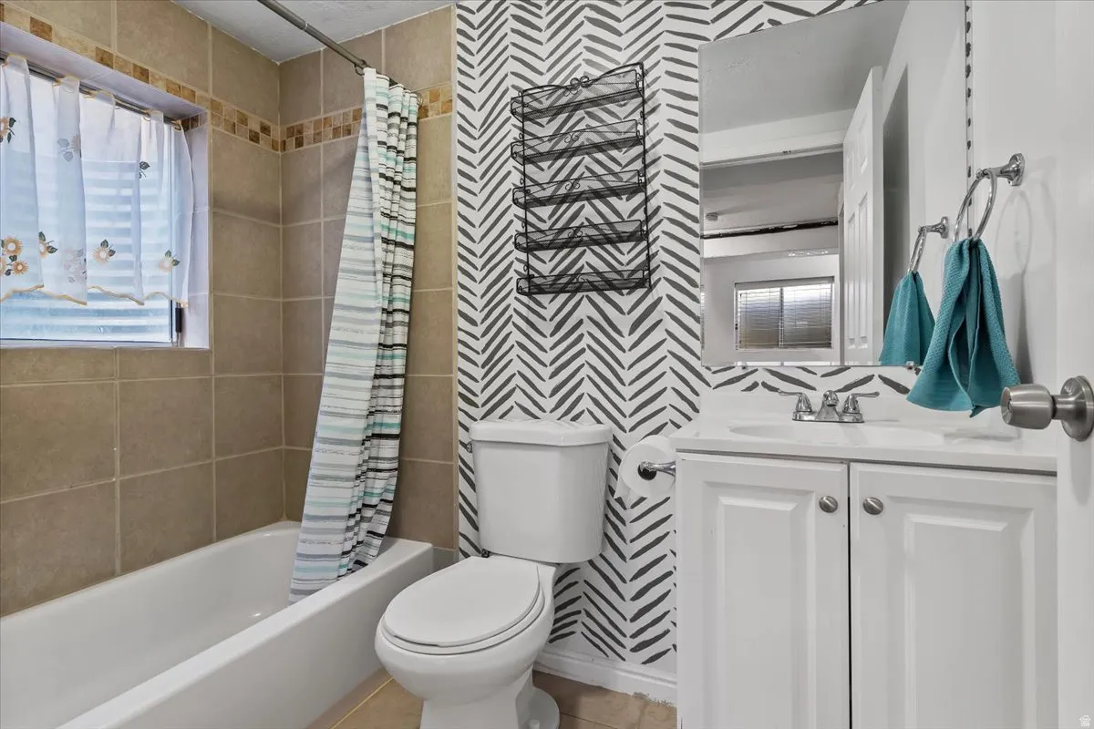 Basement Full bath with wallpapered walls, vanity, and shower / bathtub combination with curtain