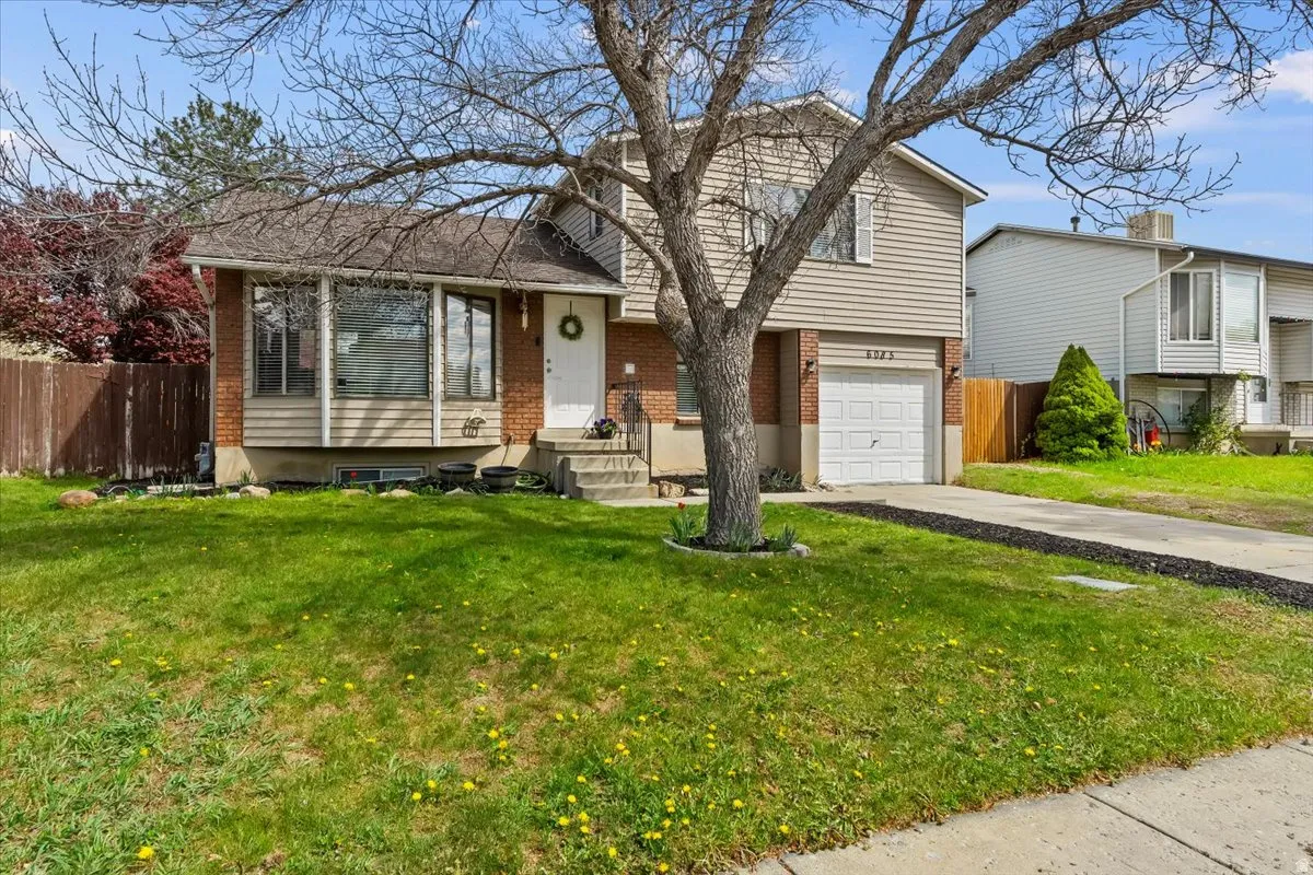 Tri-level home with brick siding, a garage, and concrete driveway