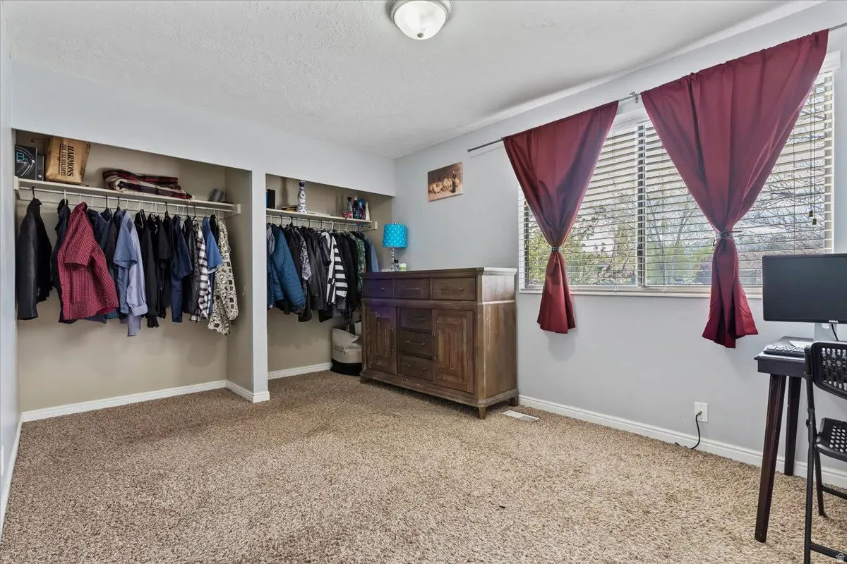 Primary Bedroom featuring light carpet, a textured ceiling, and multiple closets