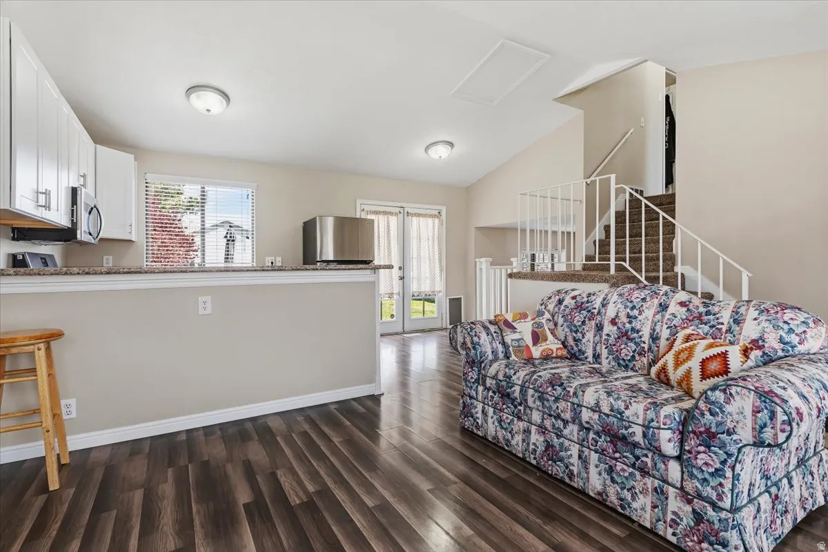 Living area with healthy amount of natural light, vaulted ceiling, and dark wood-type flooring