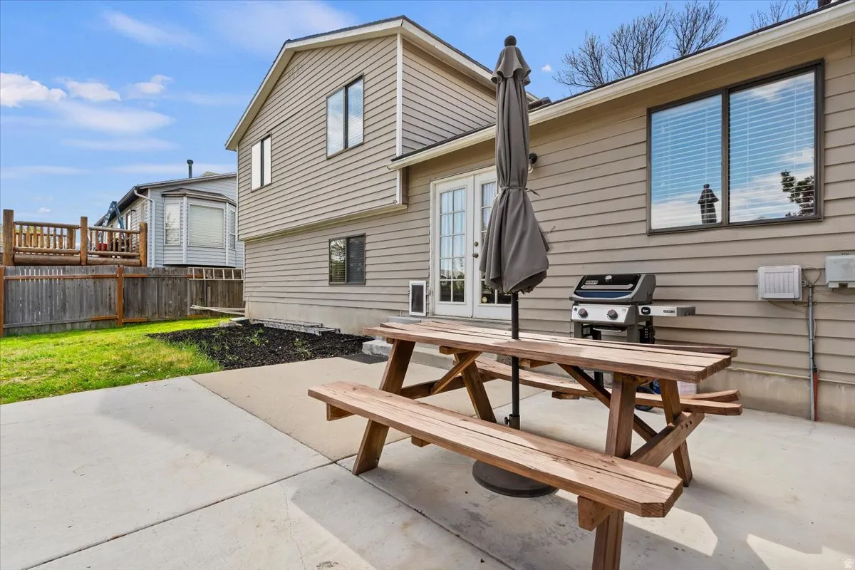 Back of property with a large patio, french doors, and outdoor picnic dining space with included picnic table and umbrella.