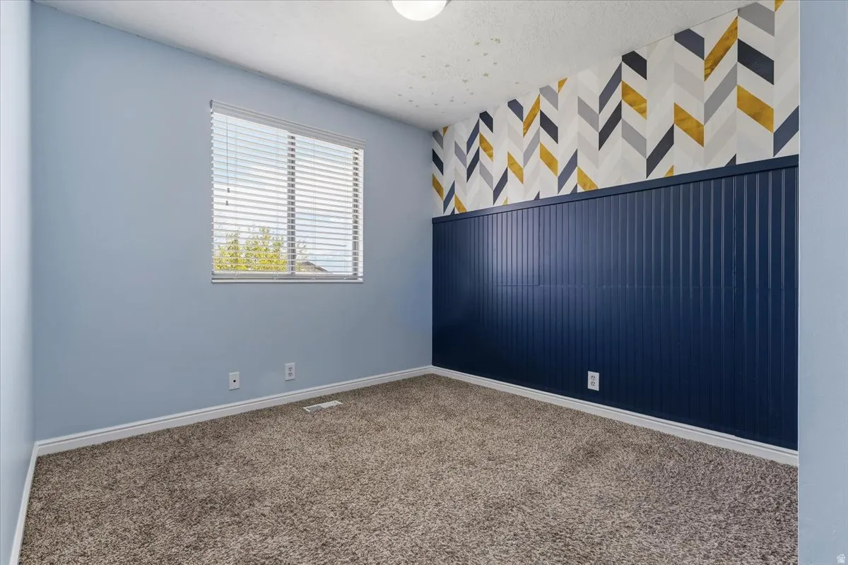 Carpeted bedroom with an accent wall, wallpapered walls, and a textured ceiling