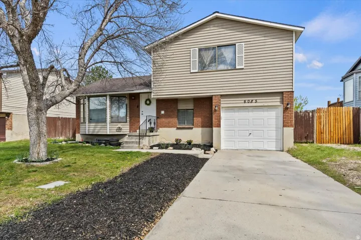 Tri-level home featuring brick siding, a garage, and concrete driveway
