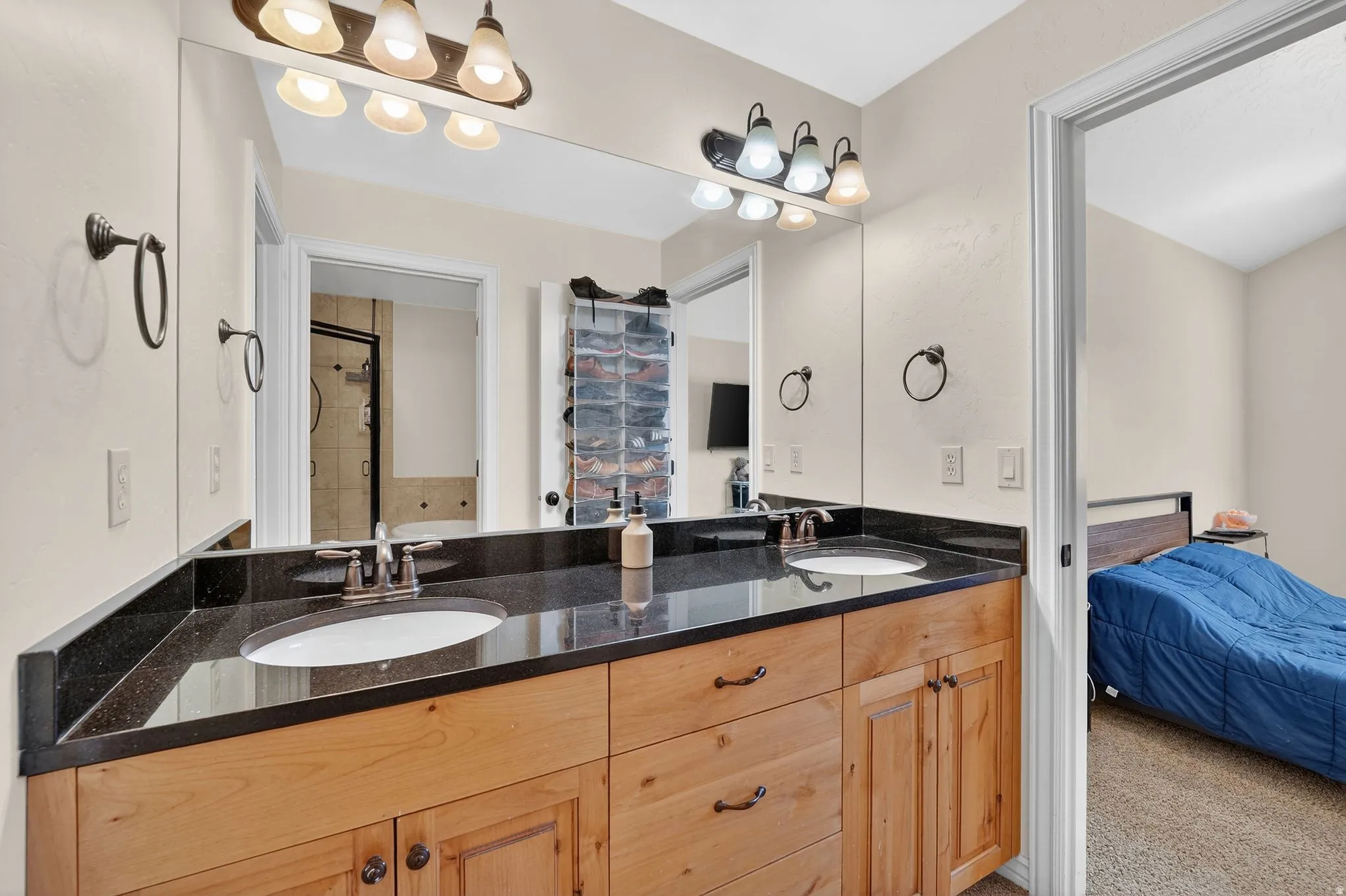 Ensuite bathroom with double vanity, a shower stall, and light carpet