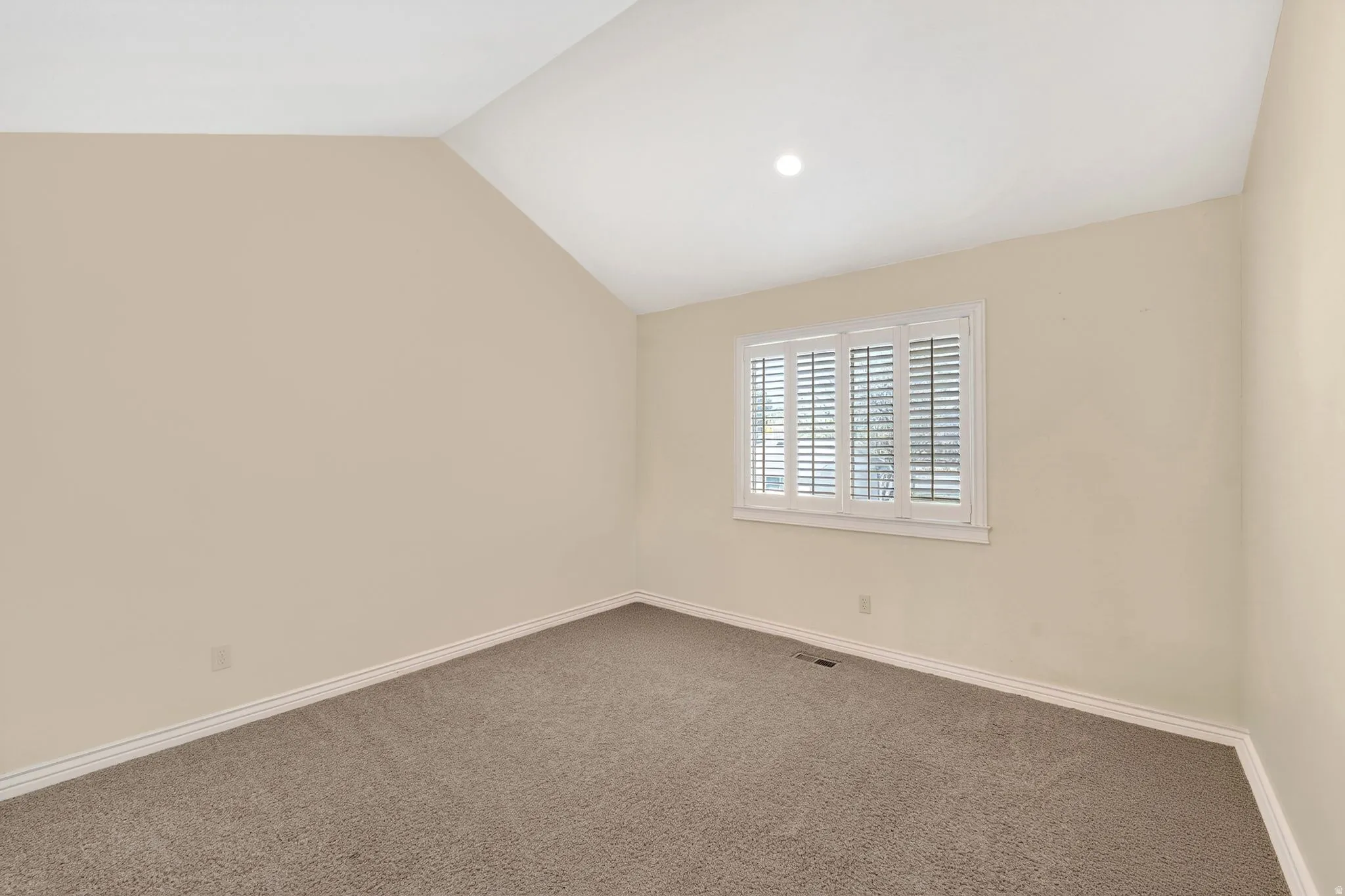 Carpeted empty room featuring baseboards and lofted ceiling
