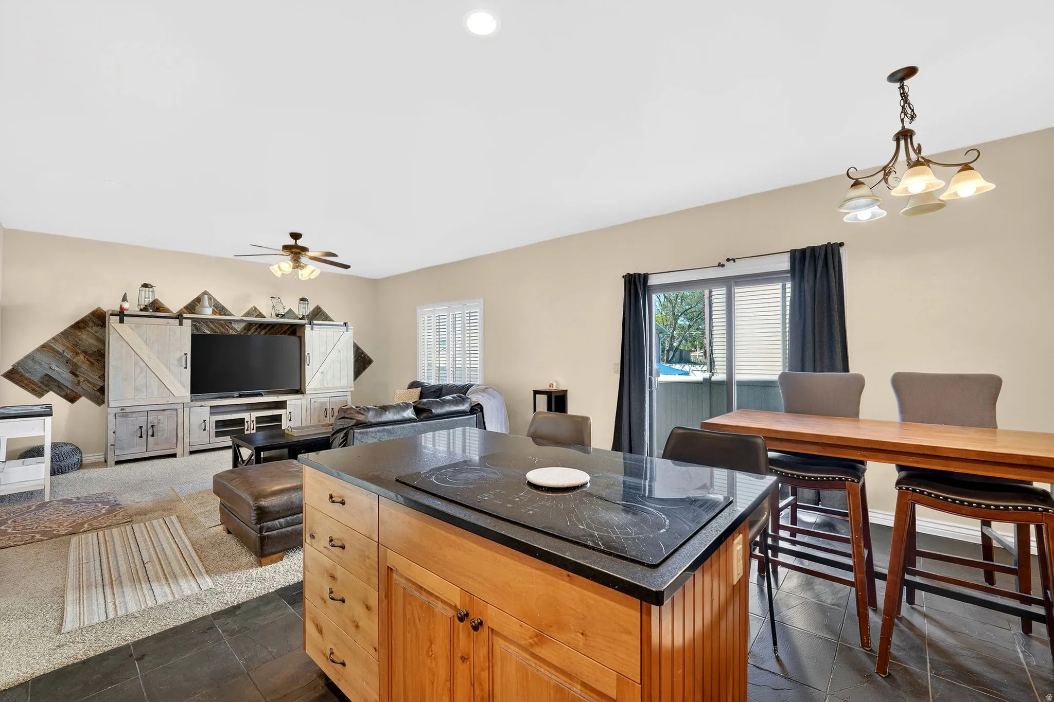 Kitchen with a center island, black electric stovetop, hanging lights, open floor plan, and light wood finish cabinetry