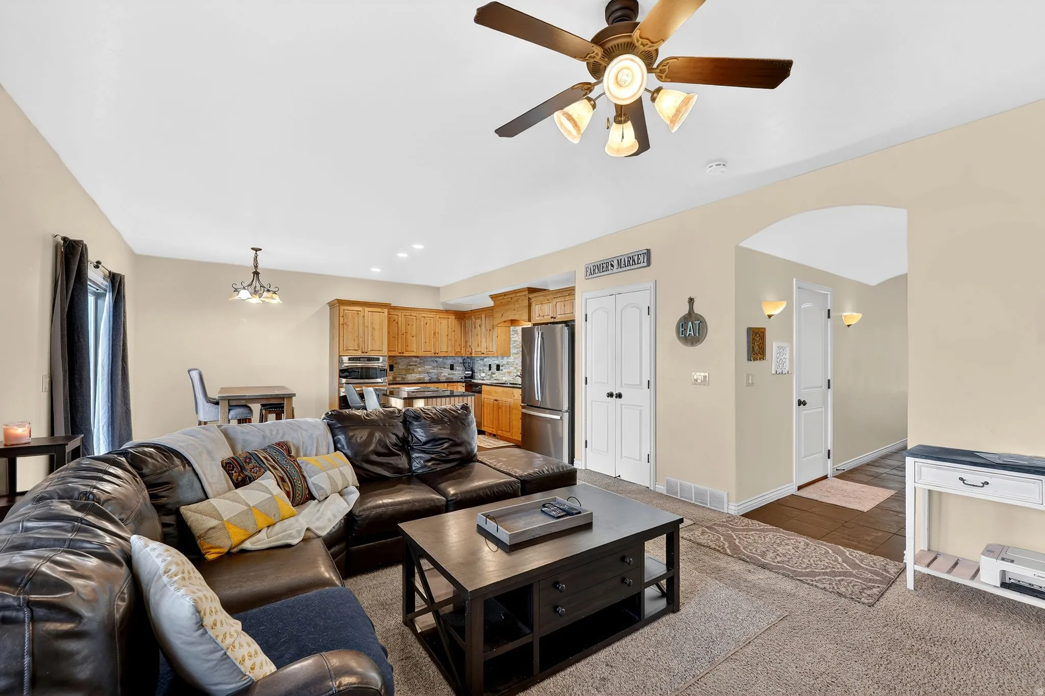 Living room featuring arched walkways, a chandelier, a ceiling fan, and carpet flooring