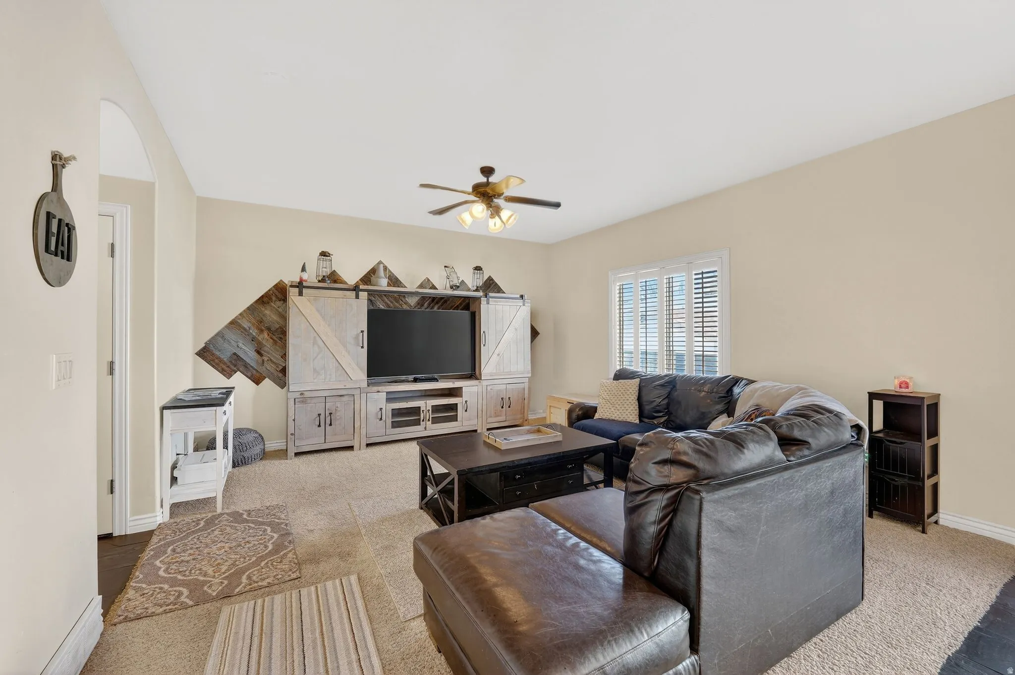 Living area with light carpet and a ceiling fan