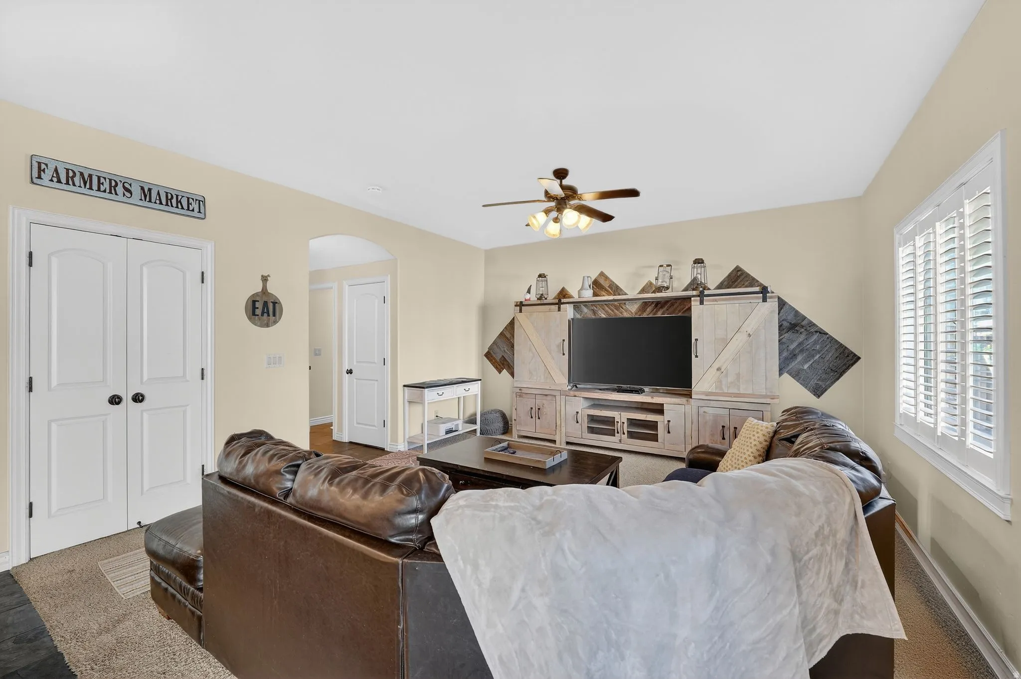 Living area with carpet flooring, arched walkways, and a ceiling fan
