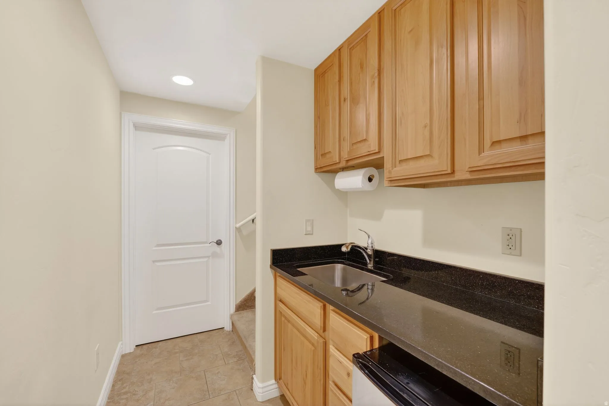 Kitchen with light wood finish cabinets, dark stone counters, recessed lighting, and dishwashing machine