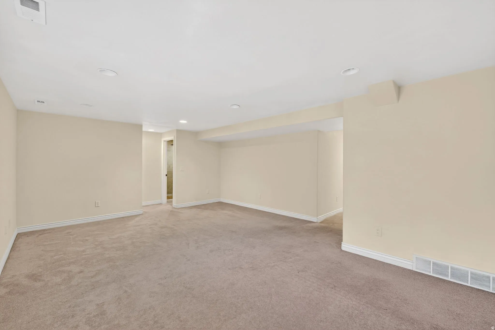 Finished basement with light carpet and recessed lighting