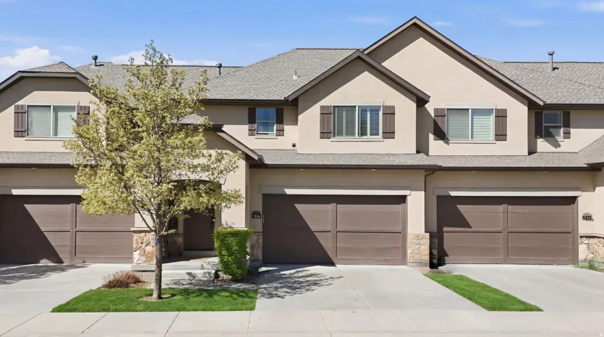 View of front facade featuring a garage, stucco siding, driveway, and stone siding