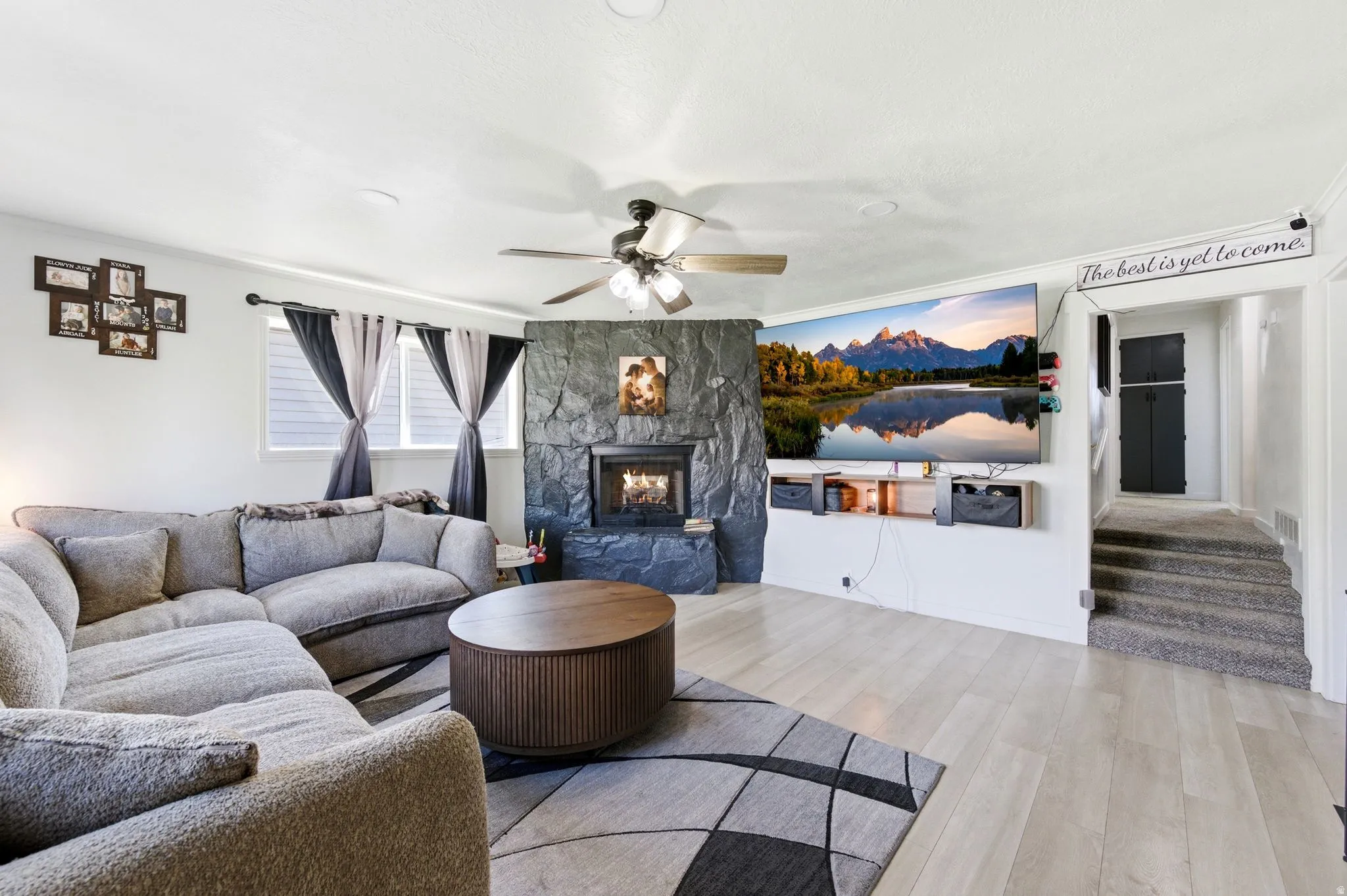 Living room with ceiling fan, wood finished floors, a fireplace, and crown molding
