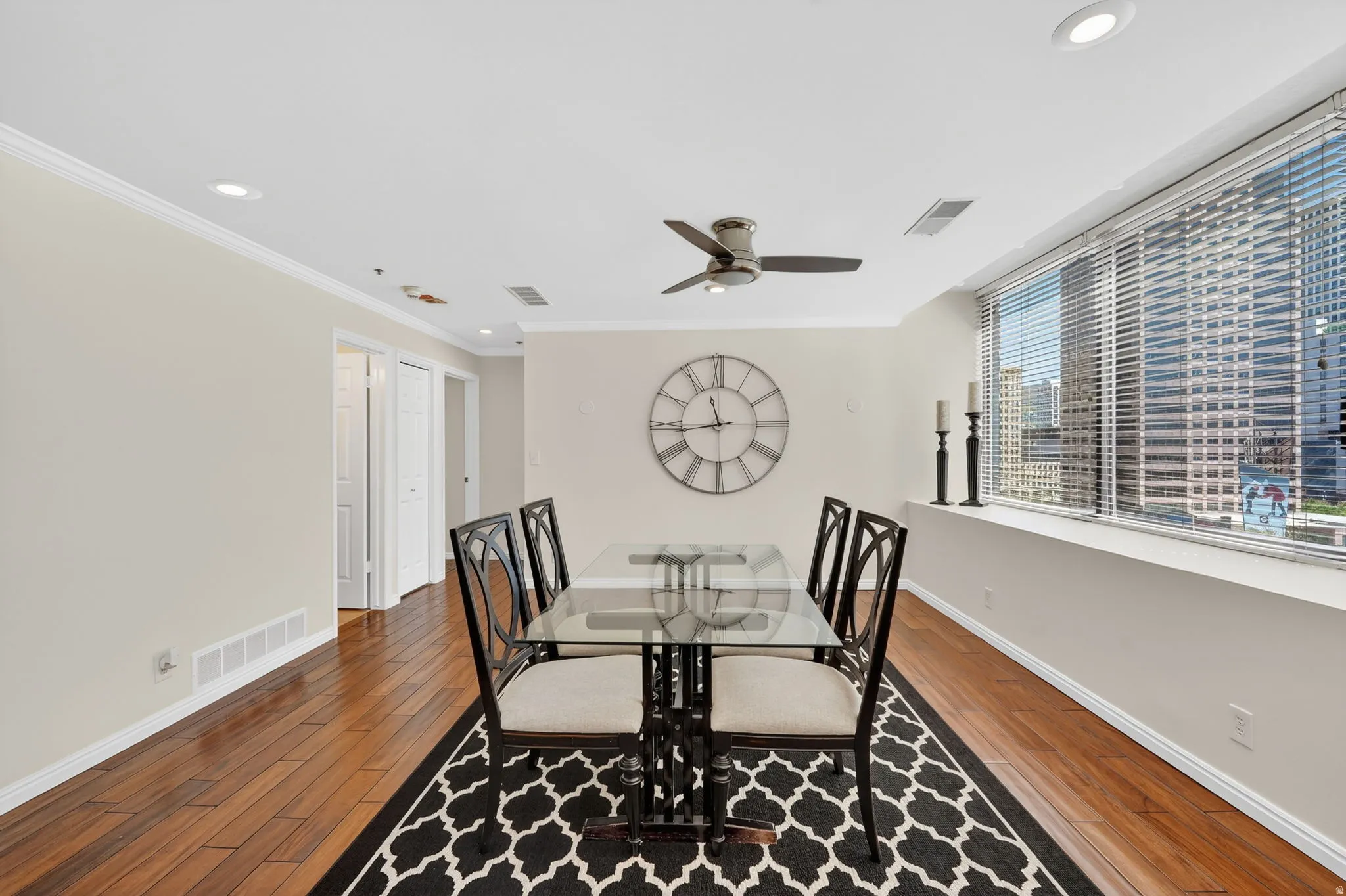 Formal dining room area with hardwood flooring, ceiling fan, recessed lighting, and ornamental molding. East facing natural lighting and large windows.