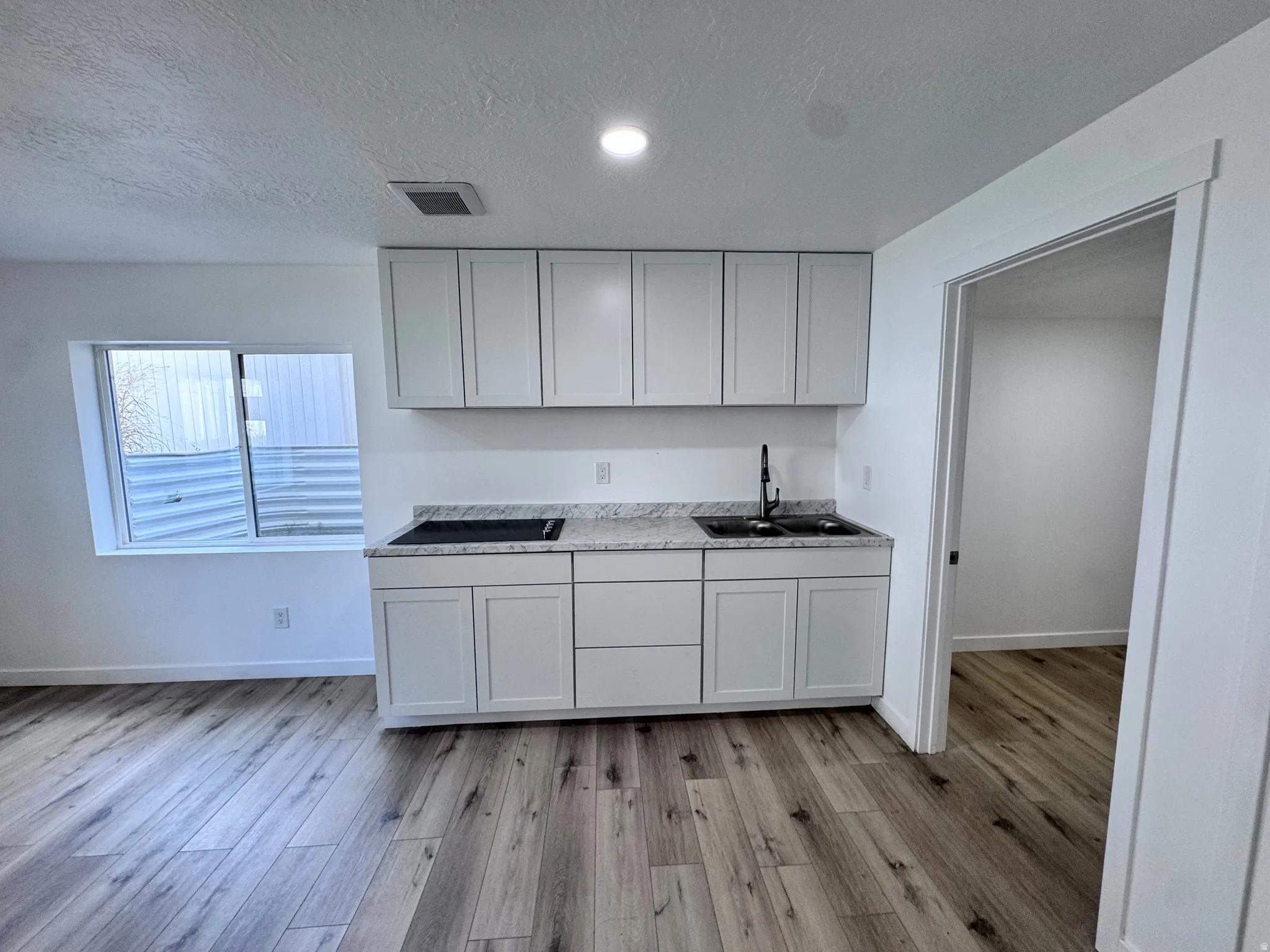Kitchen featuring light countertops, a textured ceiling, light wood-style floors, and recessed lighting