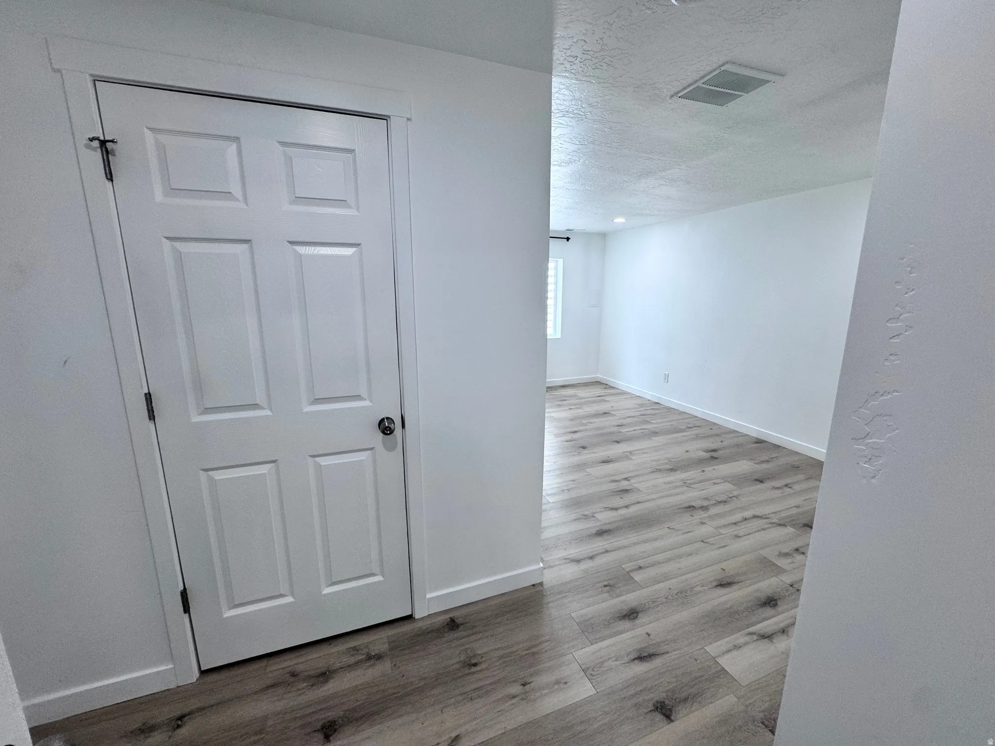 Hall featuring light wood finished floors and a textured ceiling