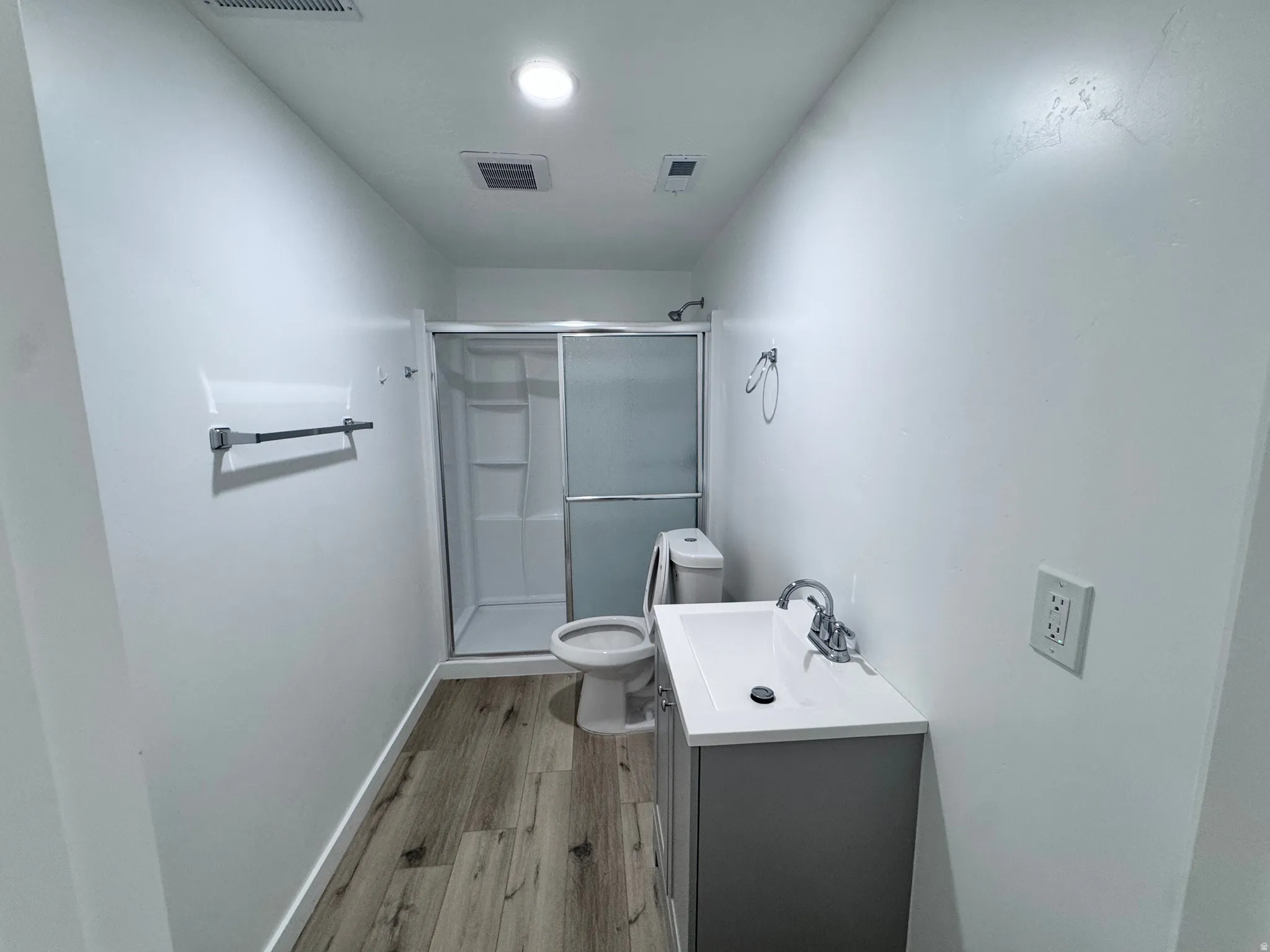 Bathroom with vanity, a stall shower, and light wood-type flooring