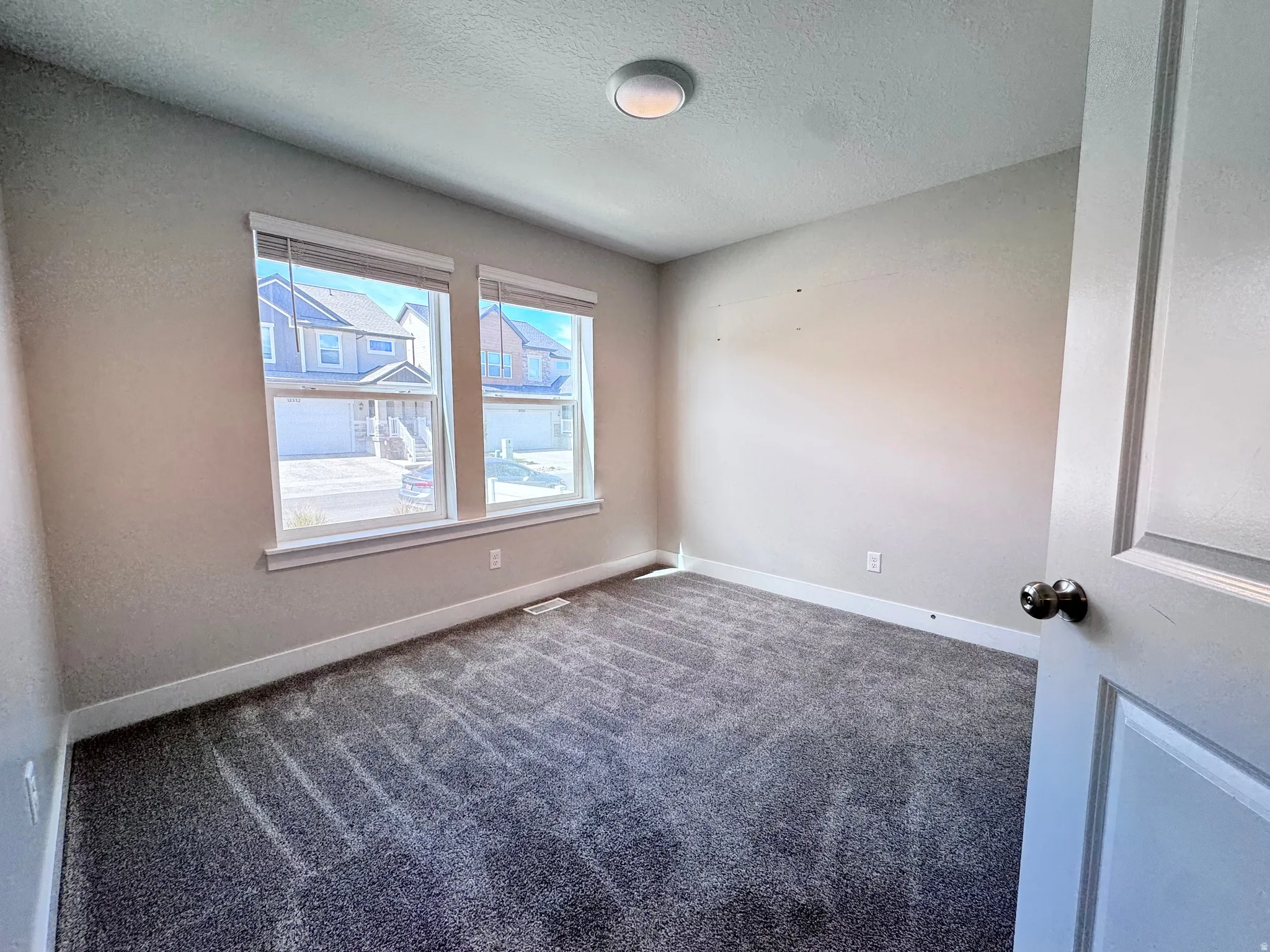 Empty room featuring carpet flooring and a textured ceiling