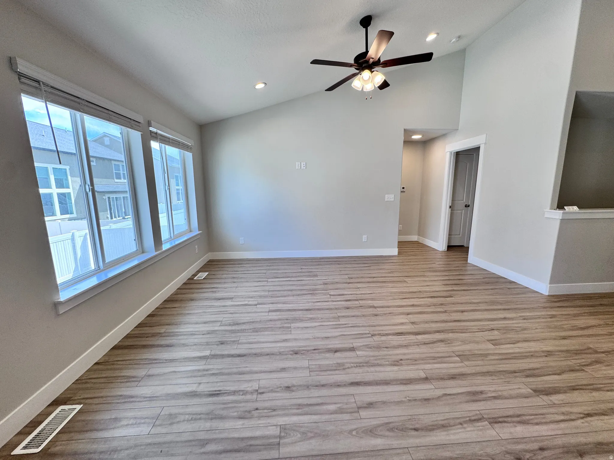 Empty room featuring a ceiling fan, light wood-style floors, vaulted ceiling, and recessed lighting